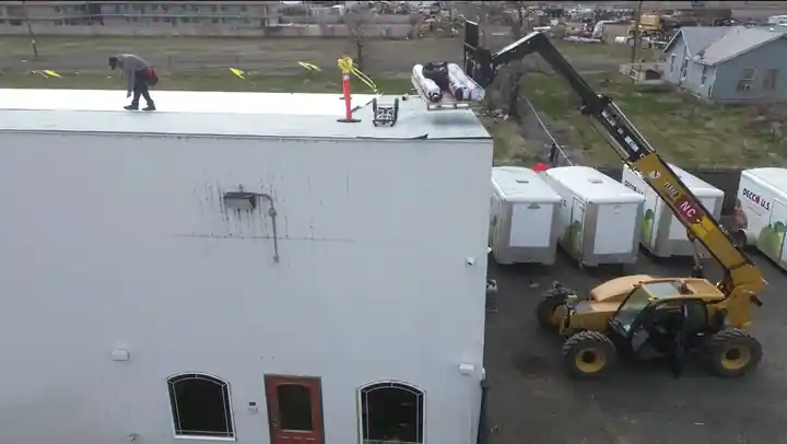 Telehandler lifting TPO rolls and supplies to the roof at Decco USA