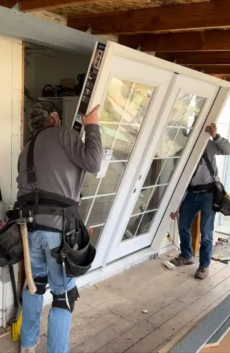 Crew members carrying a new door into place at the Gleed job
