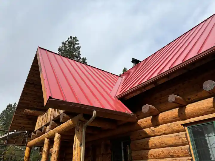 Low-angle view of a red standing seam metal roof on a log home
