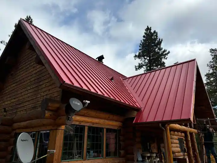 Red standing-seam metal roof on a log home, installed by Yakima Roofing & Remodeling