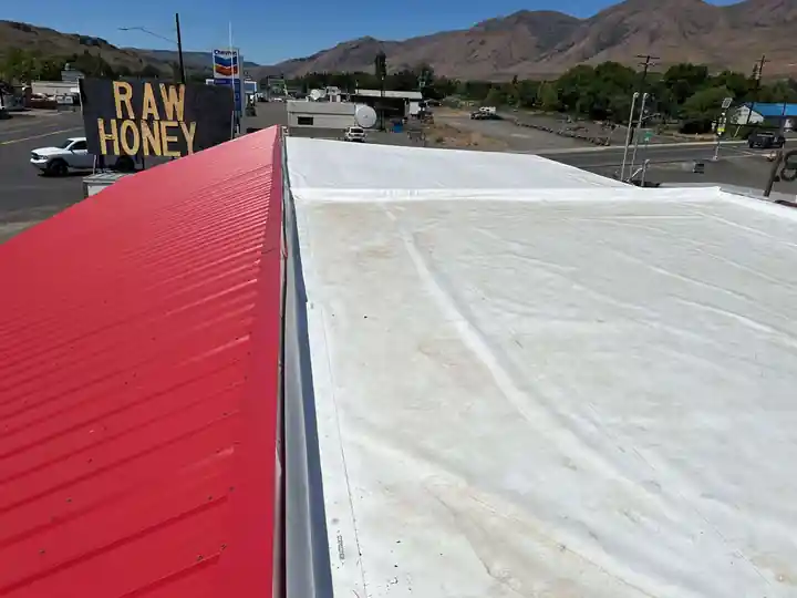 Finished white 60 mil TPO roof beside a red metal roof at the Naches Fruit Stand, Naches WA