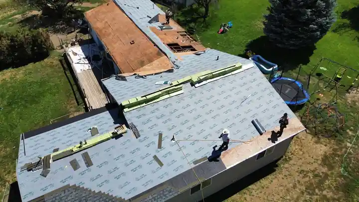Drone view of a Yakima Roofing crew laying synthetic underlayment over a stripped residential roof deck